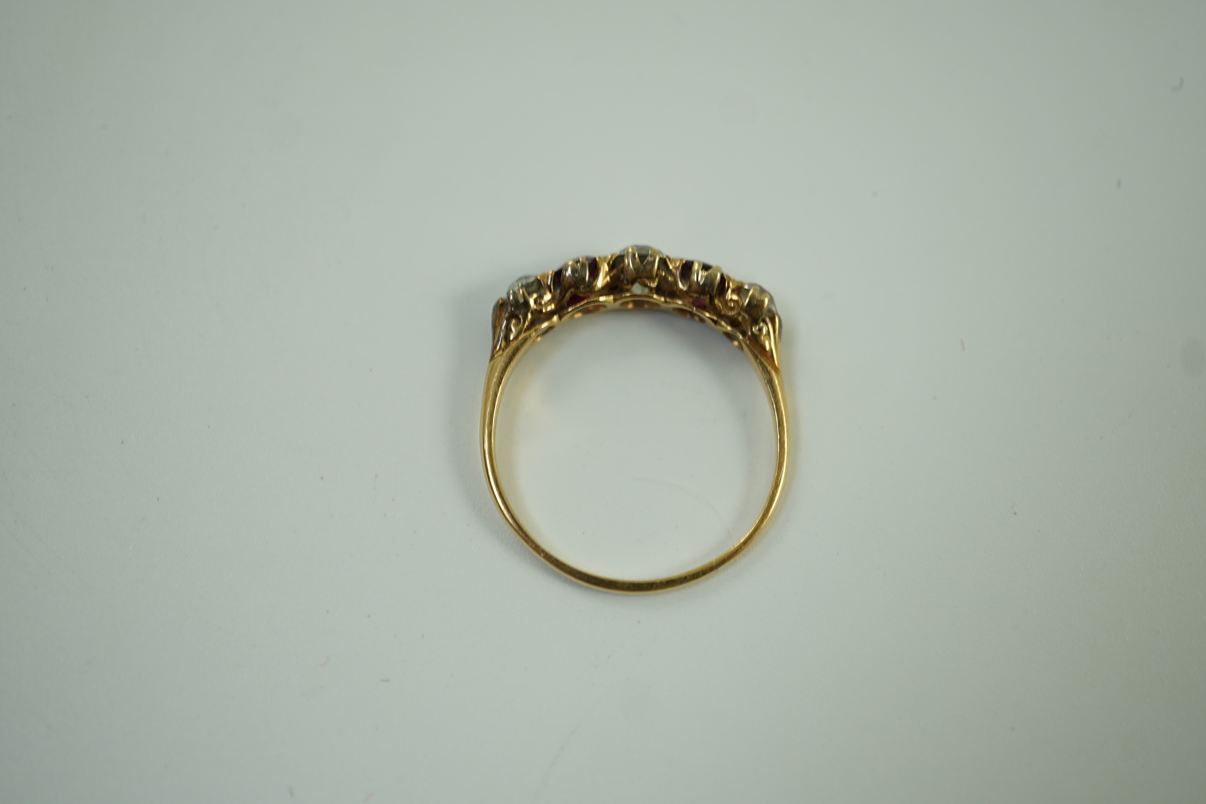 A yellow metal, three stone diamond and two stone ruby set half hoop ring, size V, gross weight 3.2 grams.